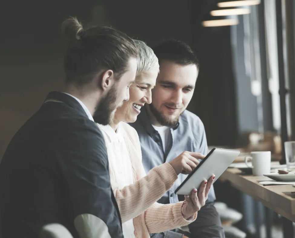 Advisor reviewing a plan on a tablet with two clients in a café