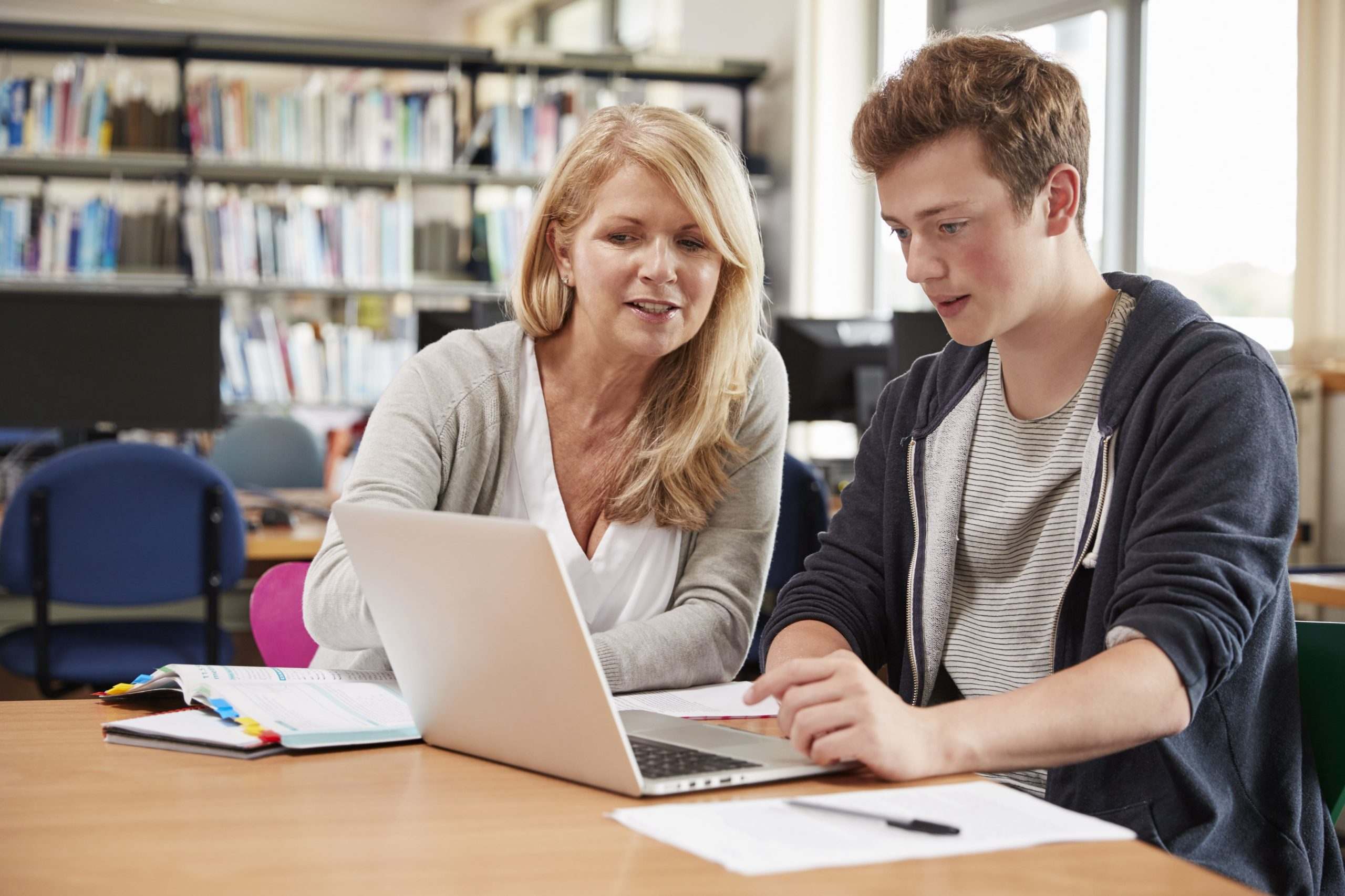 Advisor helping a high school student plan on a laptop in a library