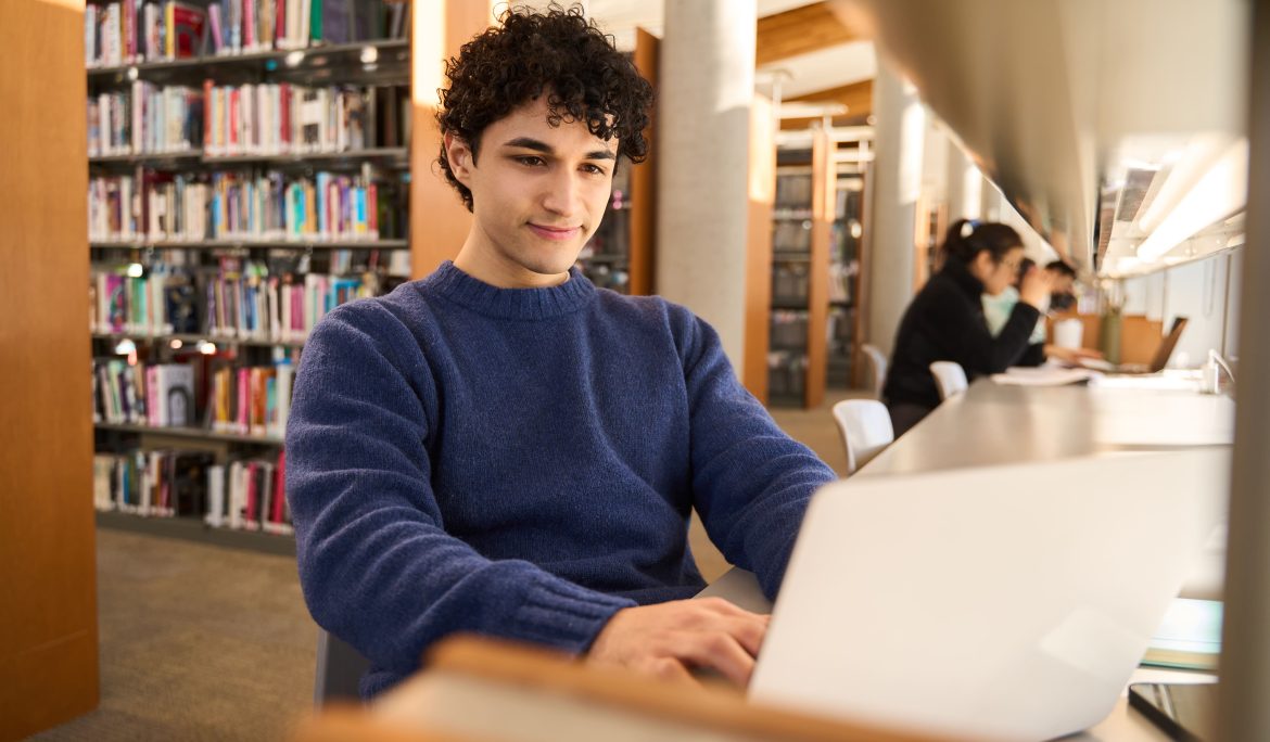 College student working on a laptop in a university library