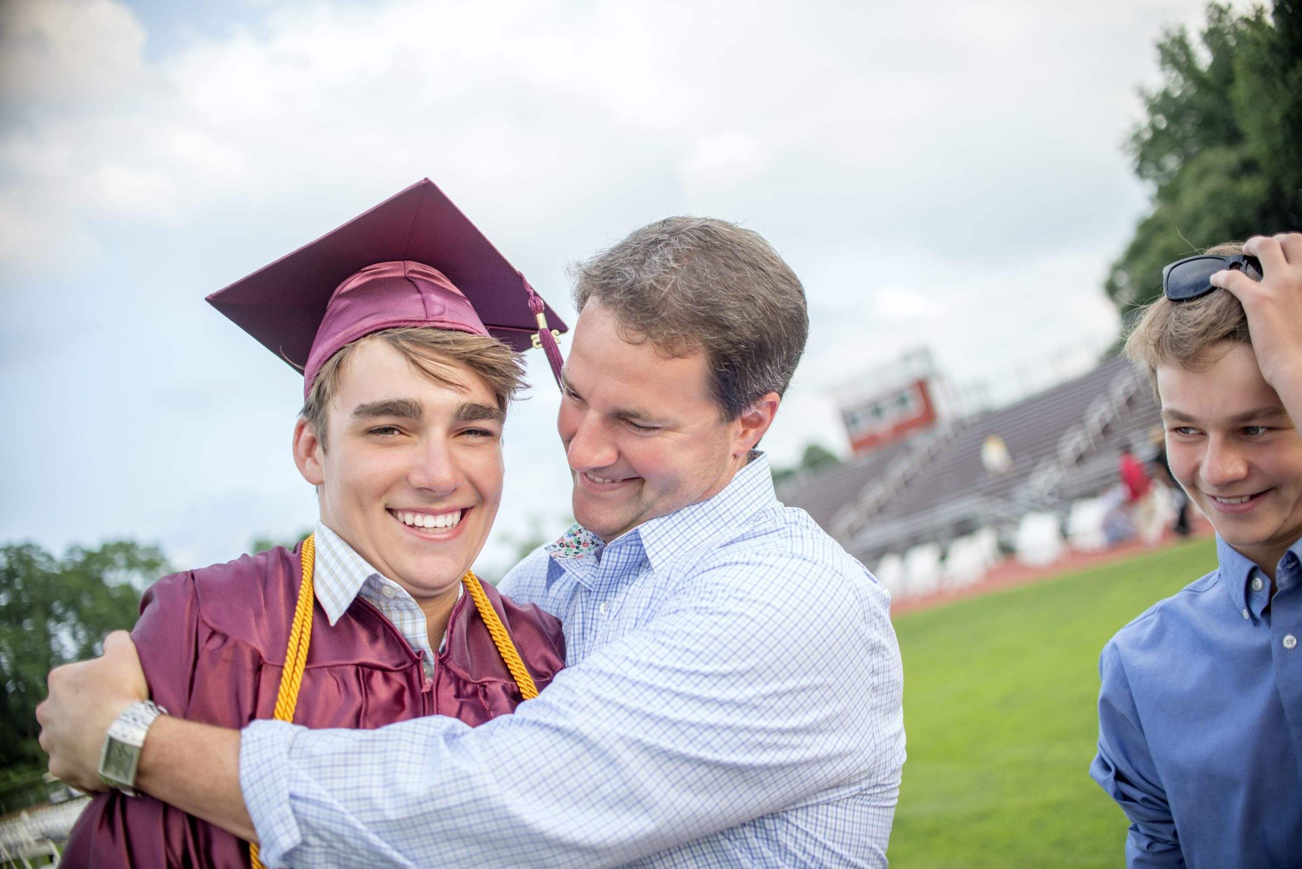 Proud father hugging his son in a graduation cap and gown