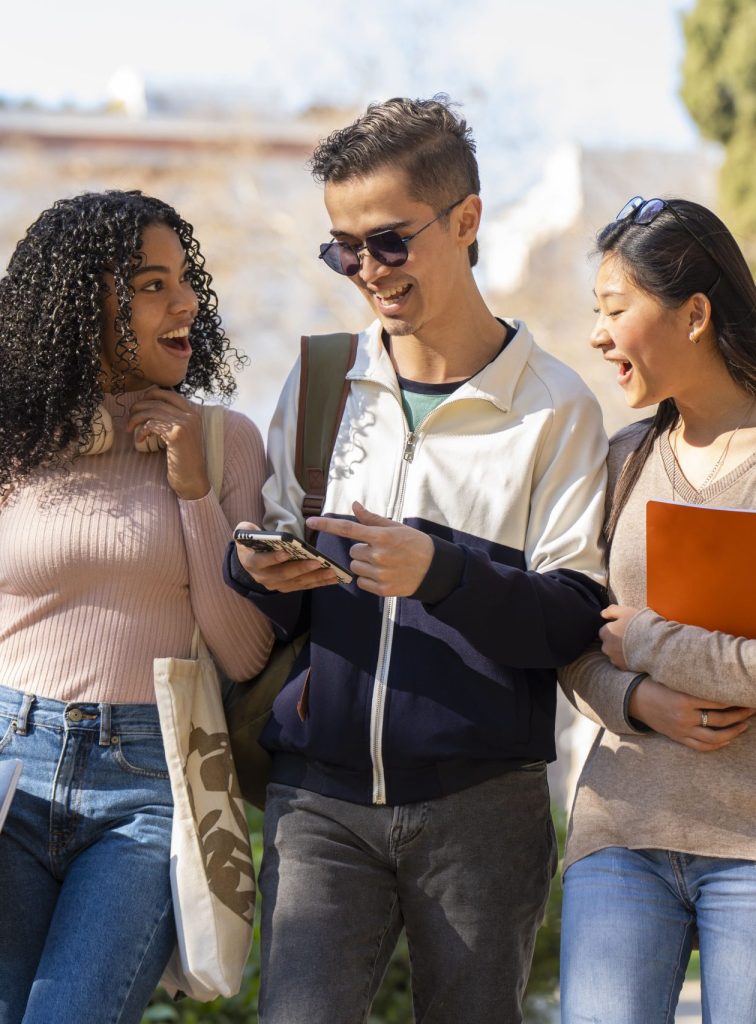 Three college students walking together and looking at a phone