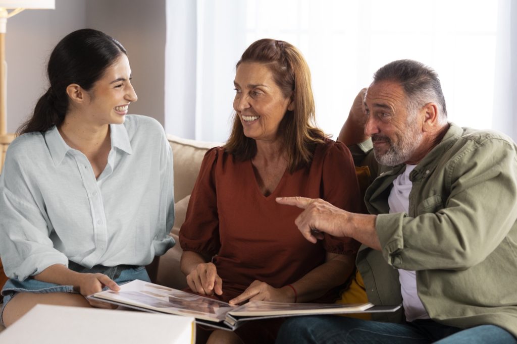 A mother, father and daughter smiling as they look through a photo album together